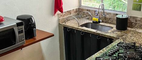 Een keuken met een granieten aanrecht, een fornuis, een magnetron en een spoelbak.
