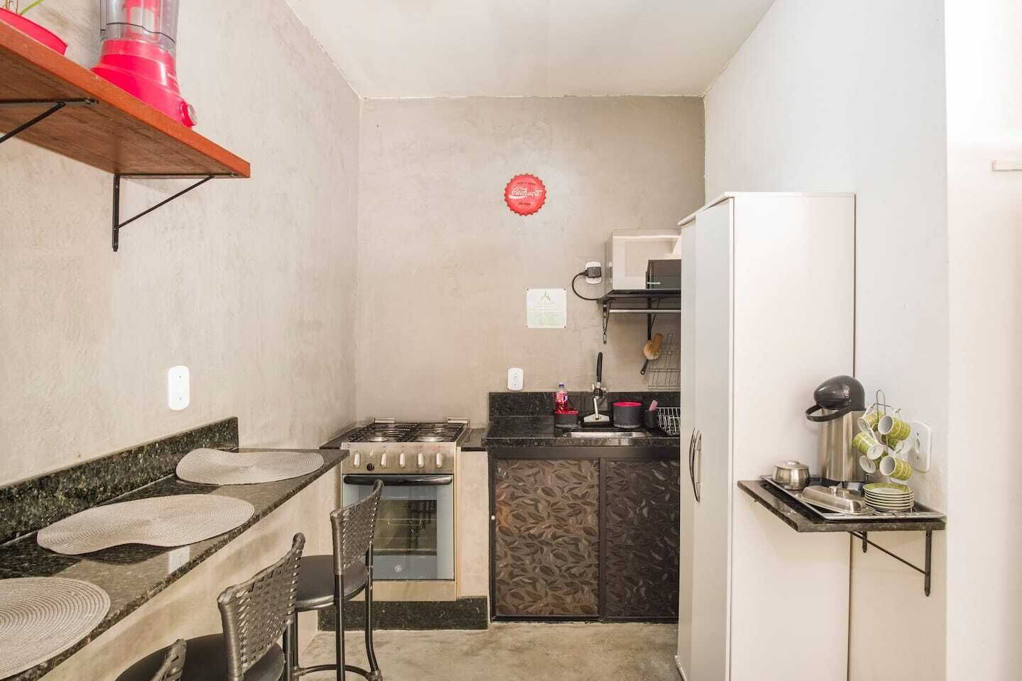 A compact kitchen with a gas stove, oven, and a refrigerator. There is a small dining area with a chair and a table.