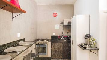 A compact kitchen with a gas stove, oven, and a refrigerator. There is a small dining area with a chair and a table.