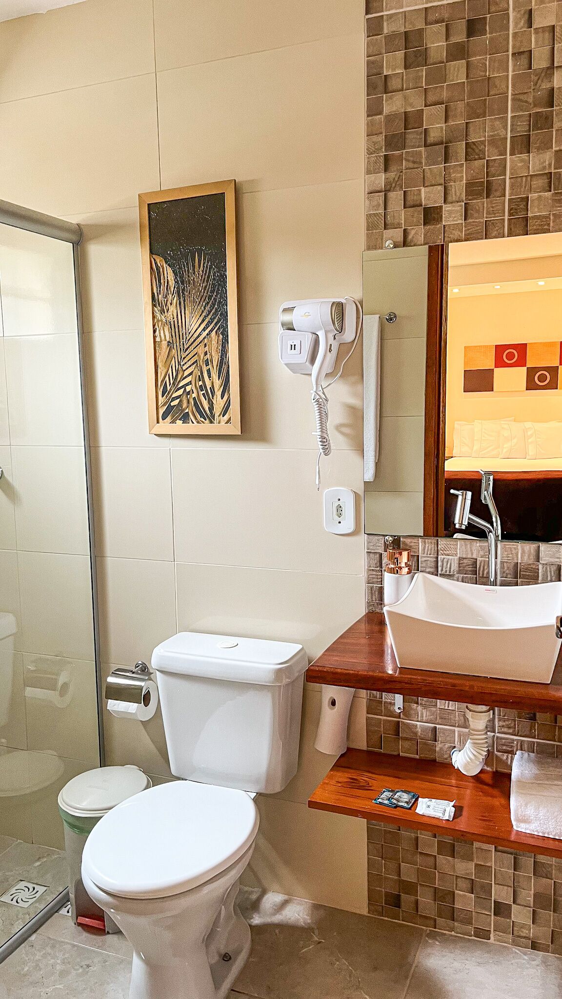 A bathroom with a toilet, a shower, a hairdryer, and a sink.