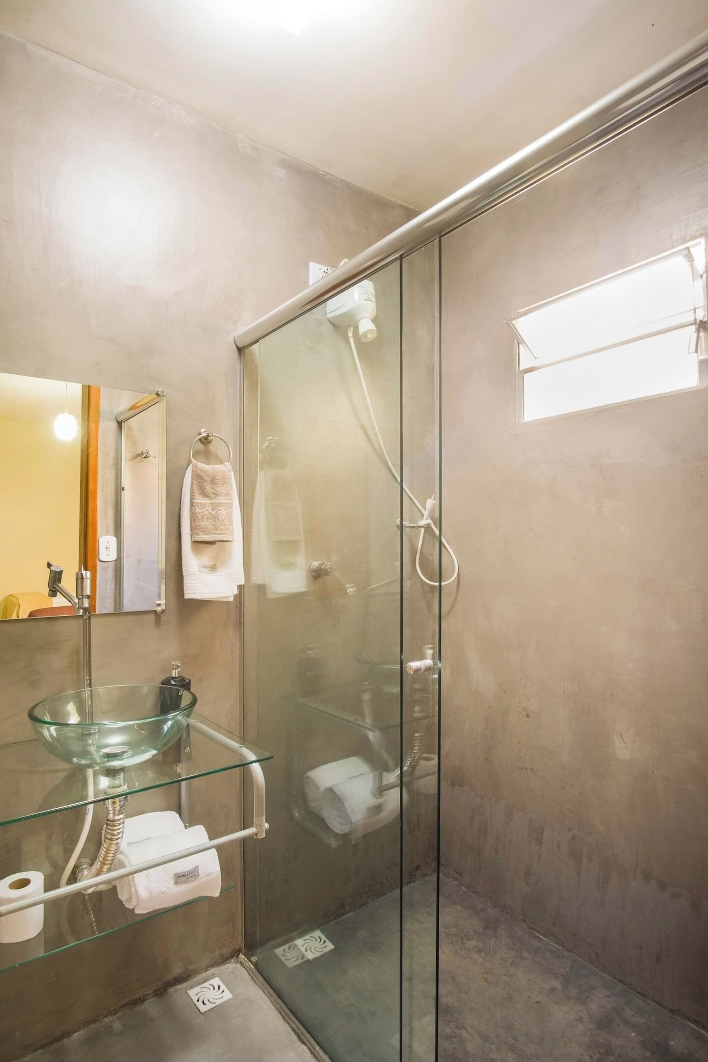 A modern bathroom with a glass-enclosed shower, a glass sink, and a mirror.