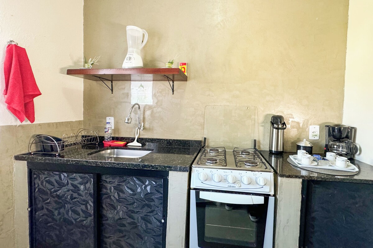 A compact kitchen with a gas stove, oven, sink, and a coffee maker.
