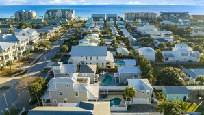 A coastal residential area with multiple two-story houses, a central road, and a view of the ocean.