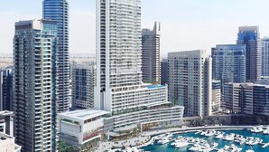 A high-rise hotel with multiple balconies, a marina with boats, and a cityscape in the background. - Vida Residences Dubai Marina (Dubai)