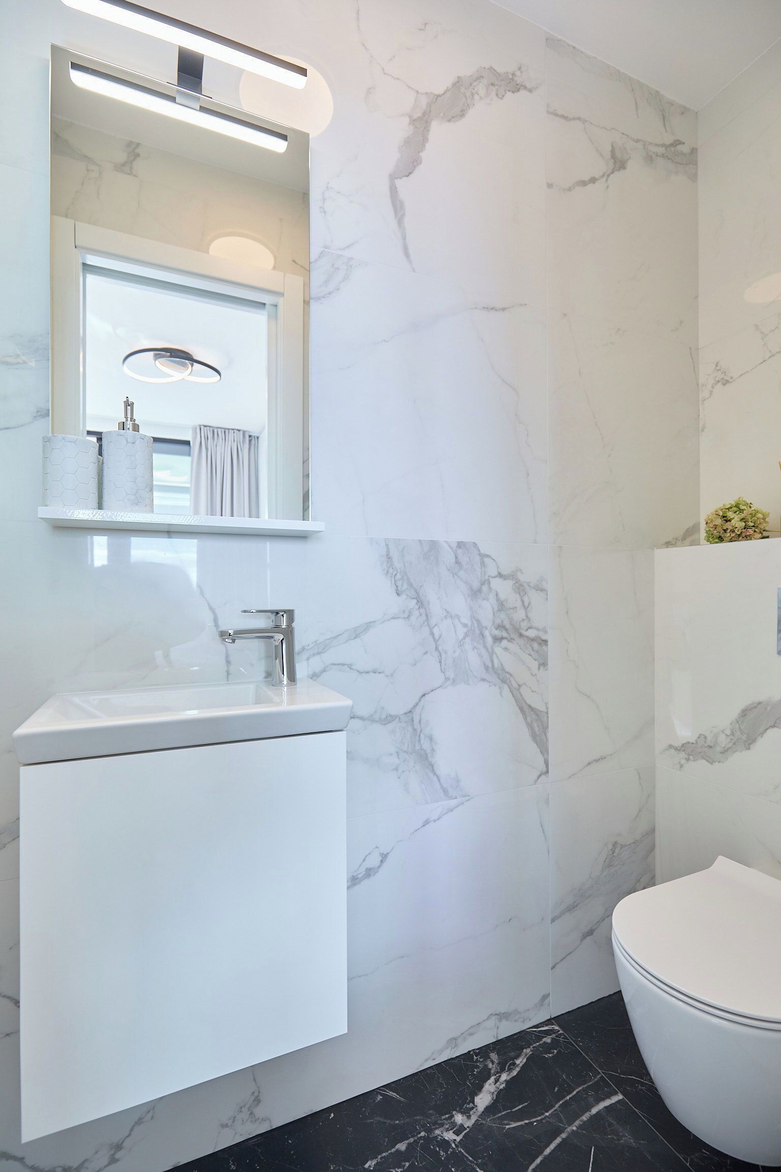 A bathroom with a white sink, a mirror, and a toilet.