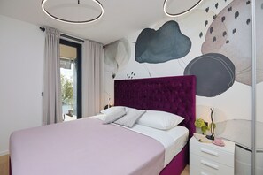 Un dormitorio moderno con una cama grande, un cabecero morado y un diseño de pared minimalista.