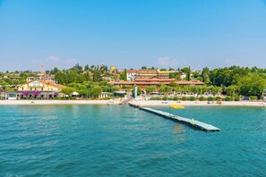 A coastal town with a pier extending into the water, surrounded by buildings and greenery.