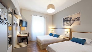 Habitación de hotel con dos camas, un escritorio con silla, un televisor y un cuadro en la pared.