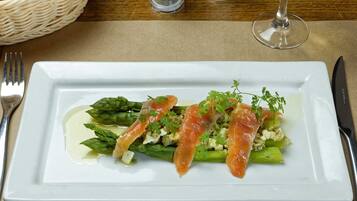 Un piatto bianco rettangolare con asparagi, salmone e guarnizione su una tovaglia beige.