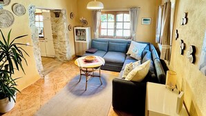 A cozy living room with a wooden ceiling, a sofa, a coffee table, and a potted plant.