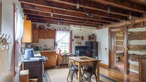 Une cuisine rustique avec des poutres en bois, un coin repas avec une table et des chaises, et un plancher en bois.