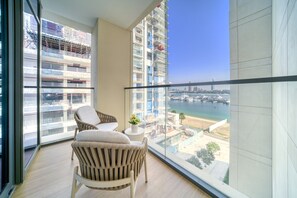 Relax on the balcony with a view of the marina and city skyline, featuring a seating area with two chairs and a table.
