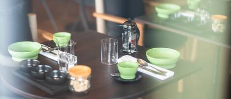 A dining table set with green bowls, glasses, and a coffee pot.