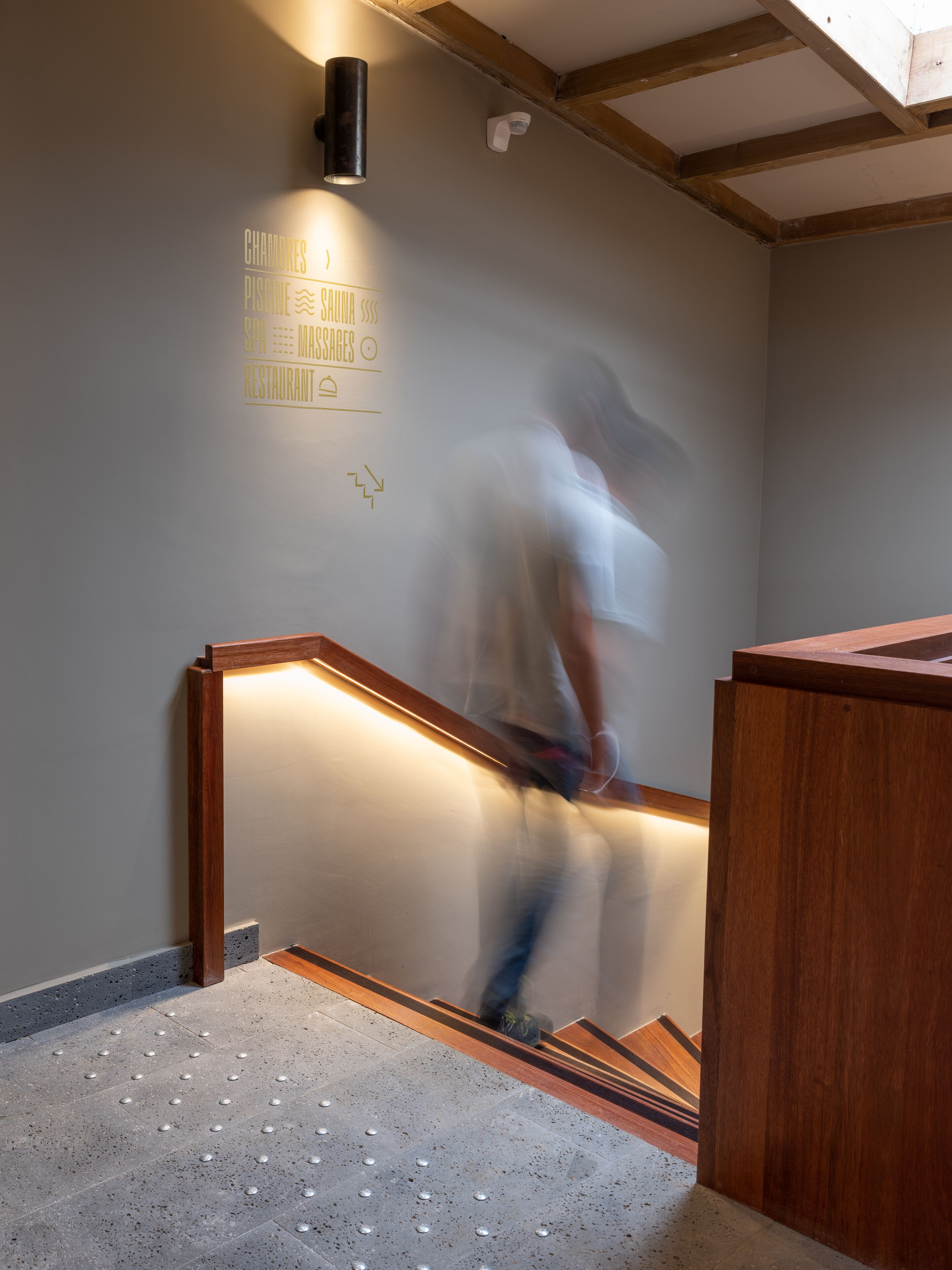 A staircase with a handrail, a wall-mounted light fixture, and a sign with text.