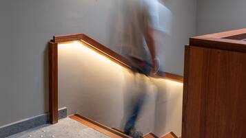 A staircase with a handrail, a wall-mounted light fixture, and a sign with text.
