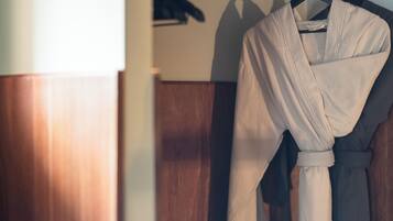 A wooden closet with a robe hanging on a rod.
