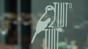 A logo with a bird and the text "TIUT TIUT" on a glass window.