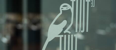Un logotipo con un pájaro y el texto 'TIUT TIUT' sobre un cristal.
