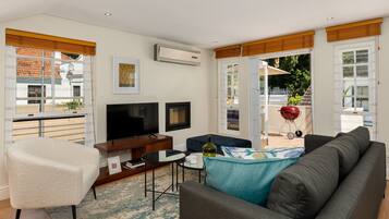 A modern living room with a sofa, armchair, TV, and a small table.