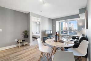 Un salon moderne avec un coin repas, des murs gris et une vue sur la ville.