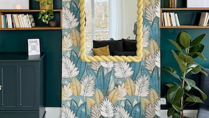 Un salón con un espejo grande, paredes color turquesa y un diseño de papel tapiz floral.