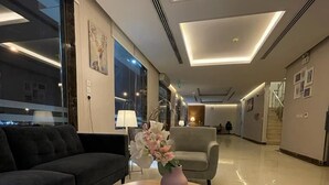 Un moderno vestíbulo de hotel con una mesa redonda de madera, un sofá y un jarrón con flores.