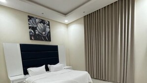 Un dormitorio moderno con una cama grande, una mesita de noche, un televisor montado en la pared y una lámpara de techo.