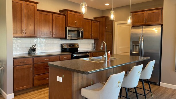 A modern kitchen with wooden cabinets, stainless steel appliances, and a central island with bar stools.
