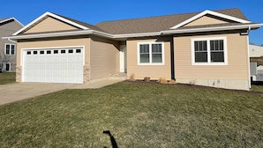 A two-story house with a garage, a front porch, and a well-maintained lawn.