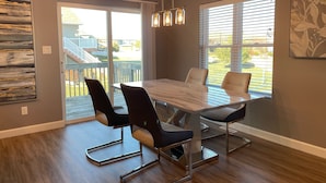 A dining area with a marble table, modern chairs, and pendant lighting.