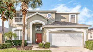 A two-story house with a garage, a red door, and a well-maintained lawn. - EV_8583 - 8 Bed 4.5 Bath Villa with Screened-In Private Pool and Access to Resor (Kissimmee)