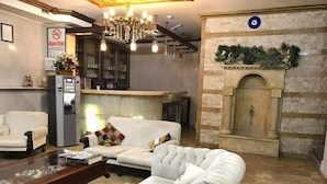 A modern lobby with a white sofa, a wooden coffee table, a chandelier, and a fireplace.
