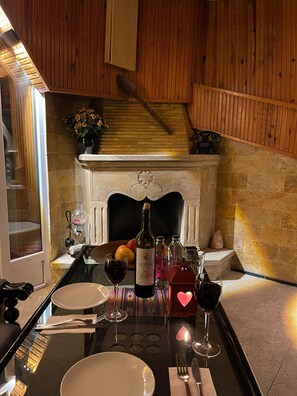 A dining table set with plates, cutlery, wine glasses, and bottles in a room with wooden walls and a fireplace. - Otel Kağıthane  (Istanbul)