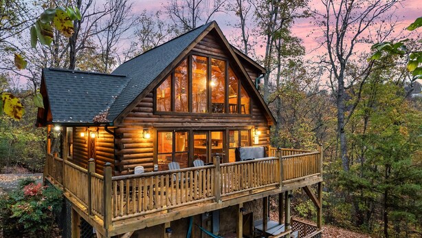 Eine Blockhütte mit Balkon, großen Fenstern und einer Veranda.