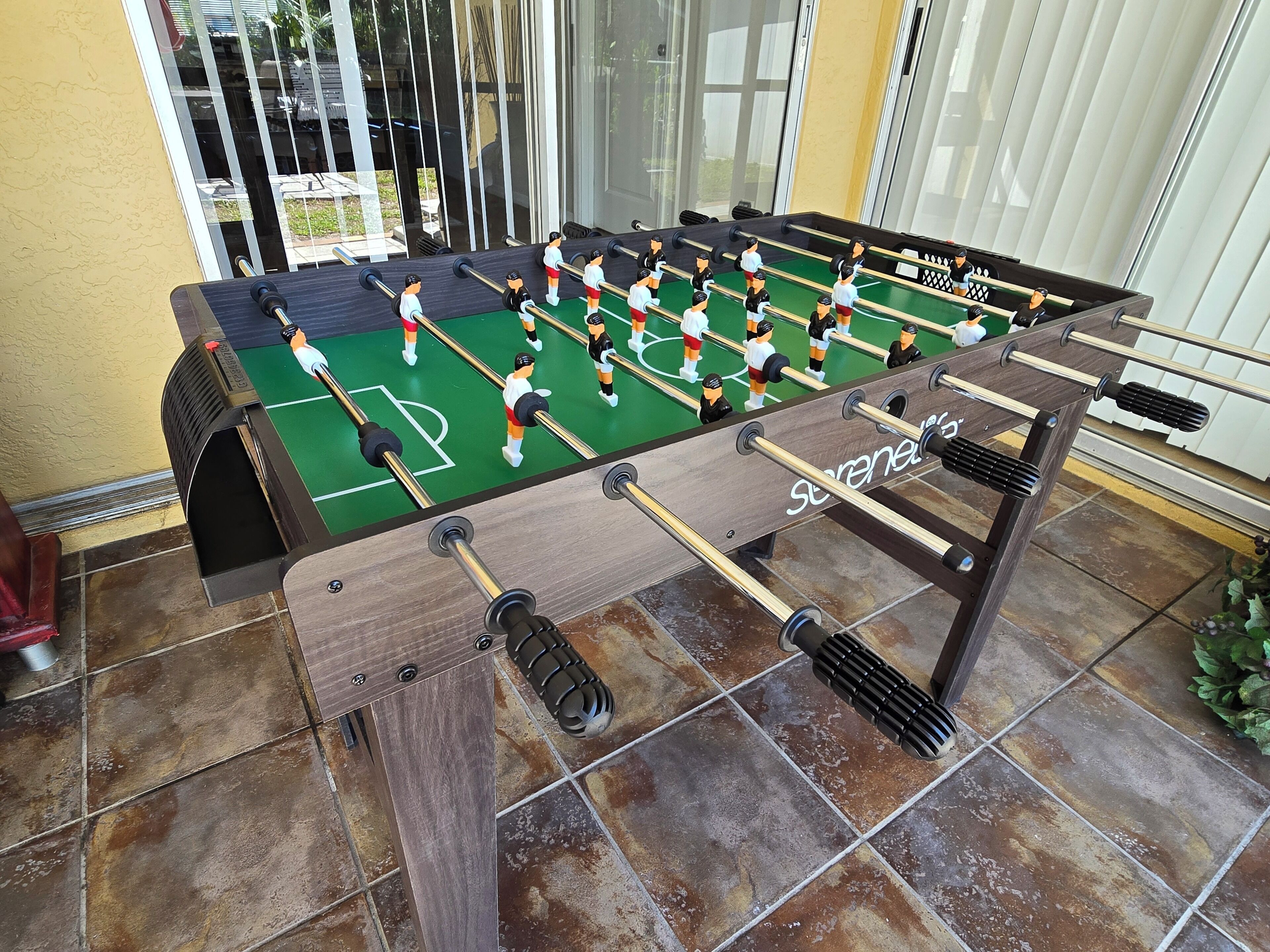 A foosball table with a wooden frame and a green playing surface.