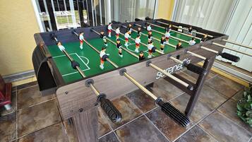 A foosball table with a wooden frame and a green playing surface.