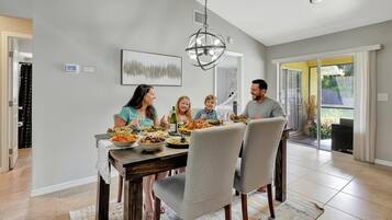 A family dining in a modern kitchen with a large dining table, chairs, and a chandelier.