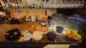 Una barra con diversos alimentos, un menú en pizarra y una selección de botellas y vasos.