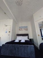 A bedroom with a bed, a painting, a chandelier, and a door with a sign.