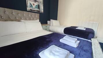 Une chambre d’hôtel avec un grand lit, un lit plus petit, une table de chevet, une commode et un radiateur.
