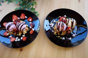 Twee zwarte borden met desserts, aardbeien en marshmallows.