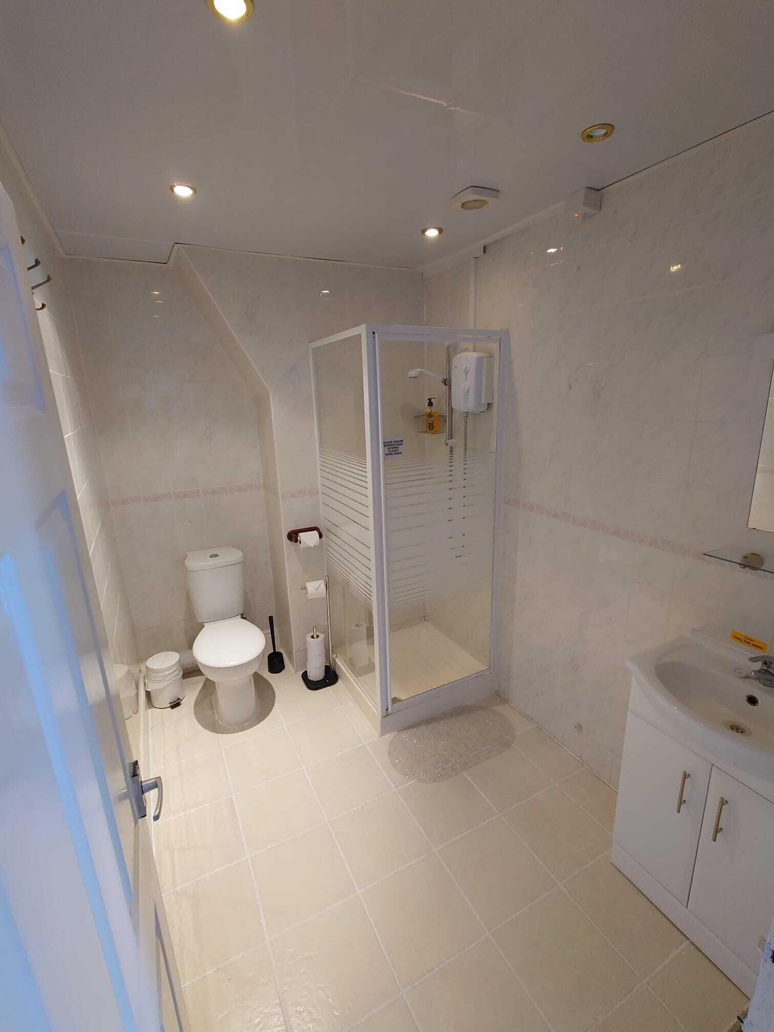 A modern bathroom with a toilet, bidet, and glass-enclosed shower.