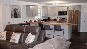Een moderne keuken met witte kastjes, een roestvrijstalen koelkast en een centraal eiland met barkrukken.