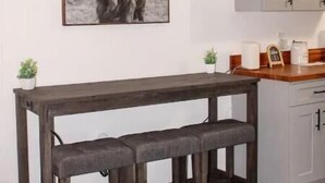 Een keuken met een houten bankje, een ingelijst beeld van een jak en witte kastjes.