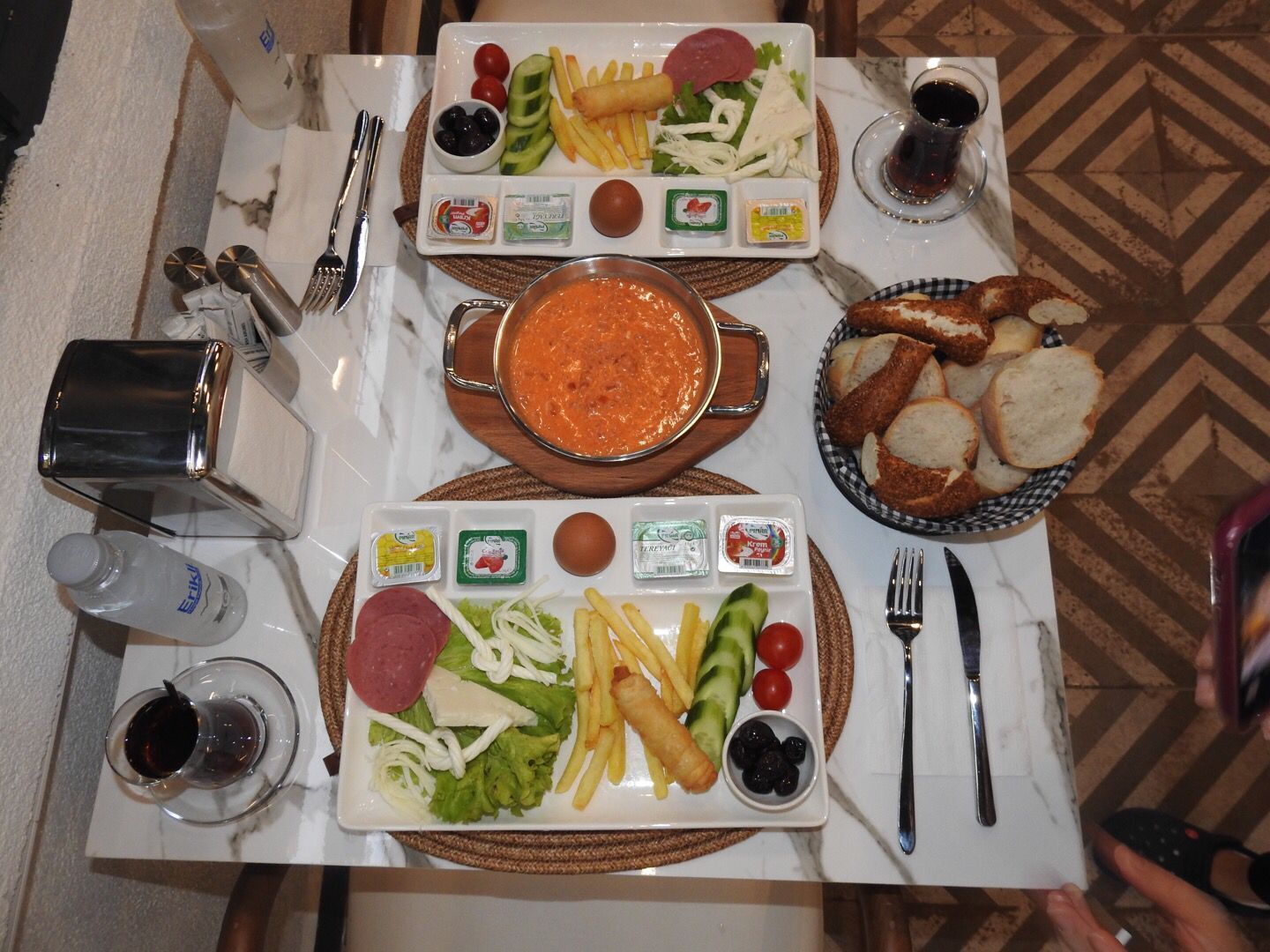 A table set with two plates of food, a bowl of soup, and a basket of bread.