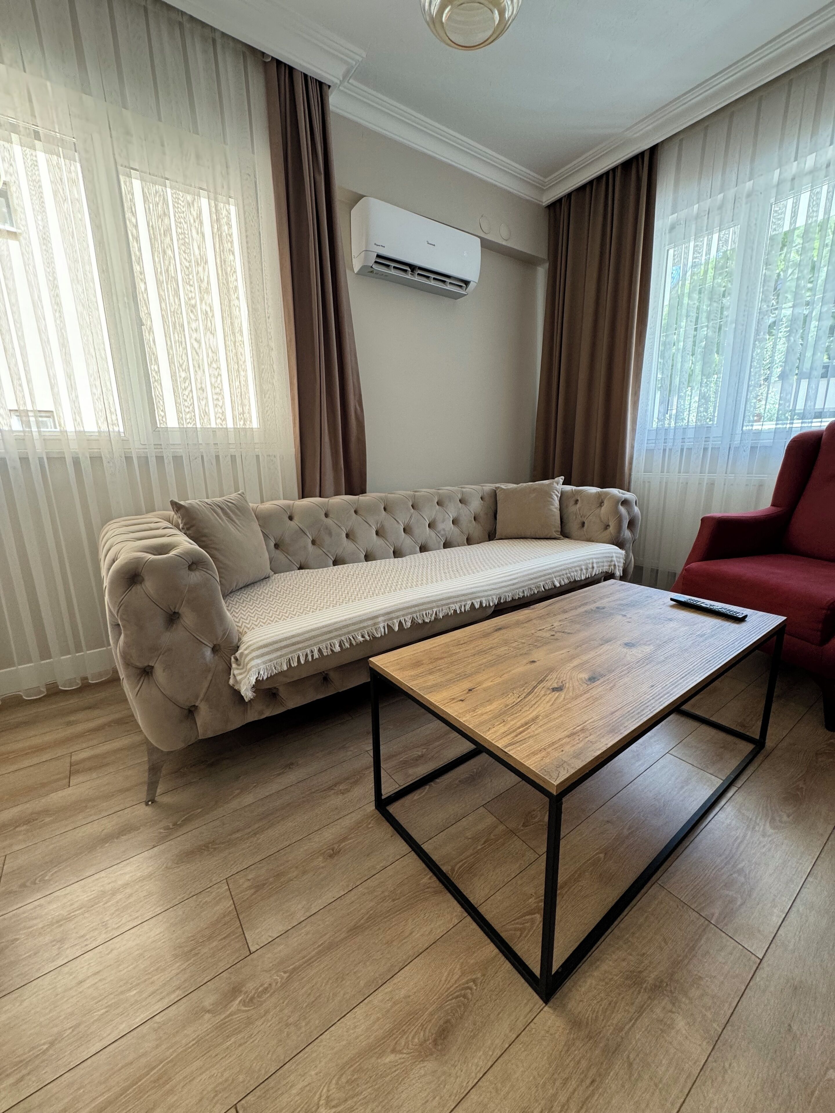 Ein Wohnzimmer mit einem beigen Sofa, einem Holztisch und einem roten Sessel.