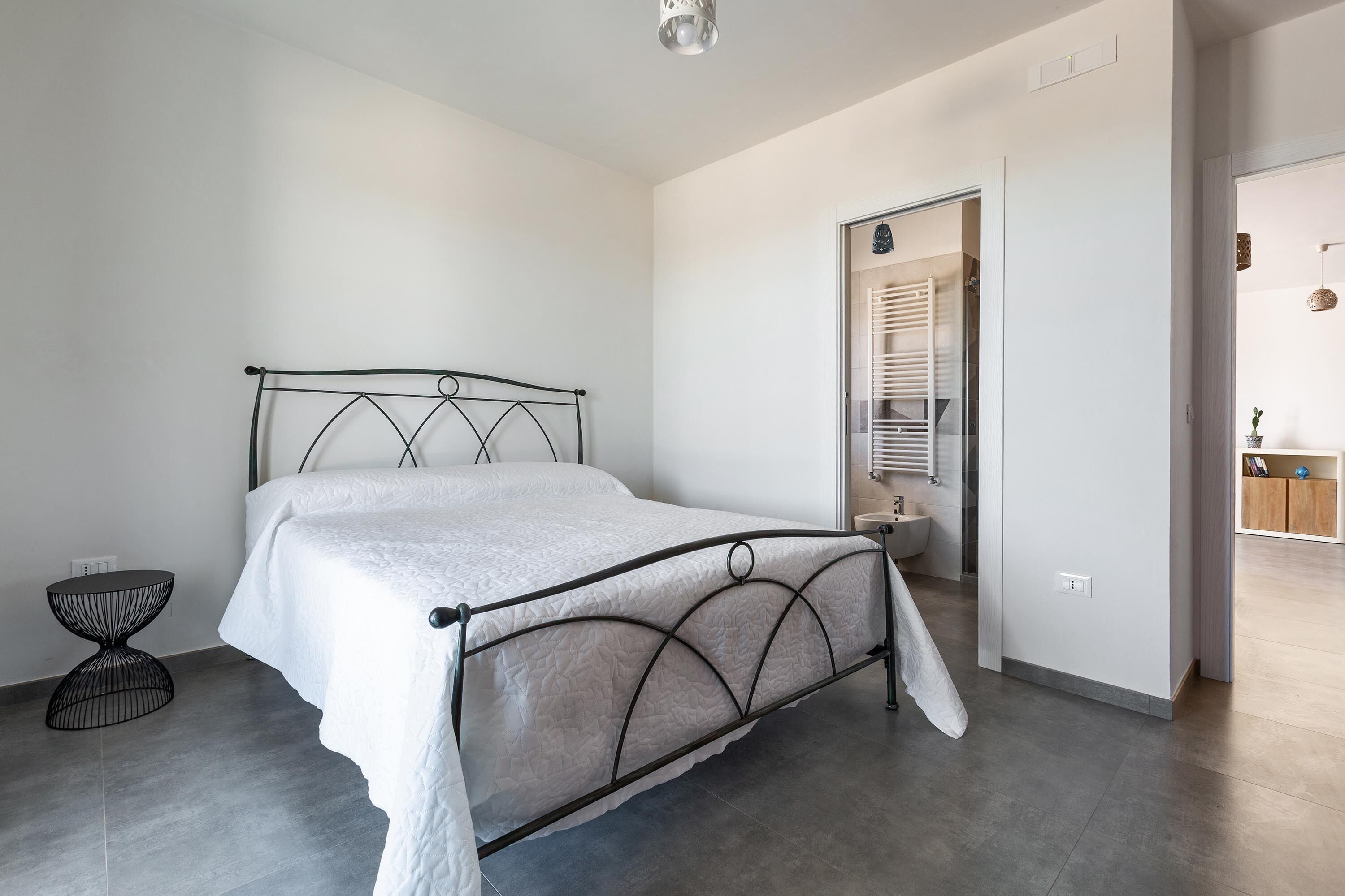 Quarto moderno com cama, uma mesinha redonda e um guarda-roupa.