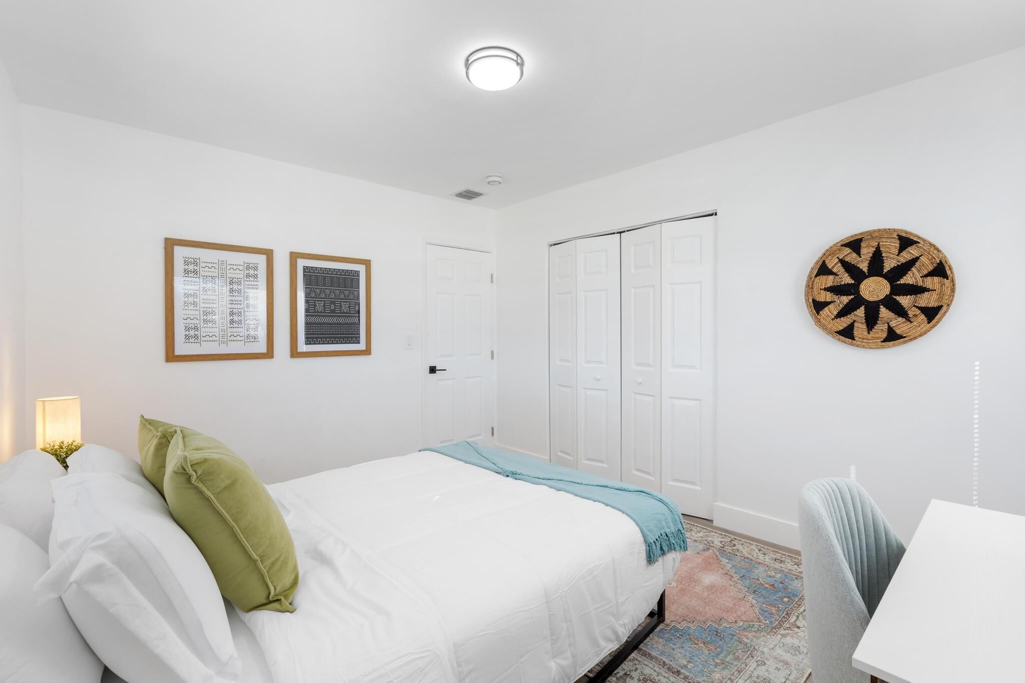 A bedroom with a bed, a desk, and a wardrobe.