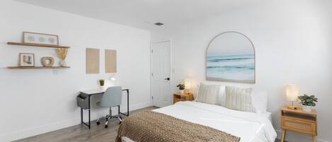 A bedroom with a bed, bedside tables, a desk, and a chair.