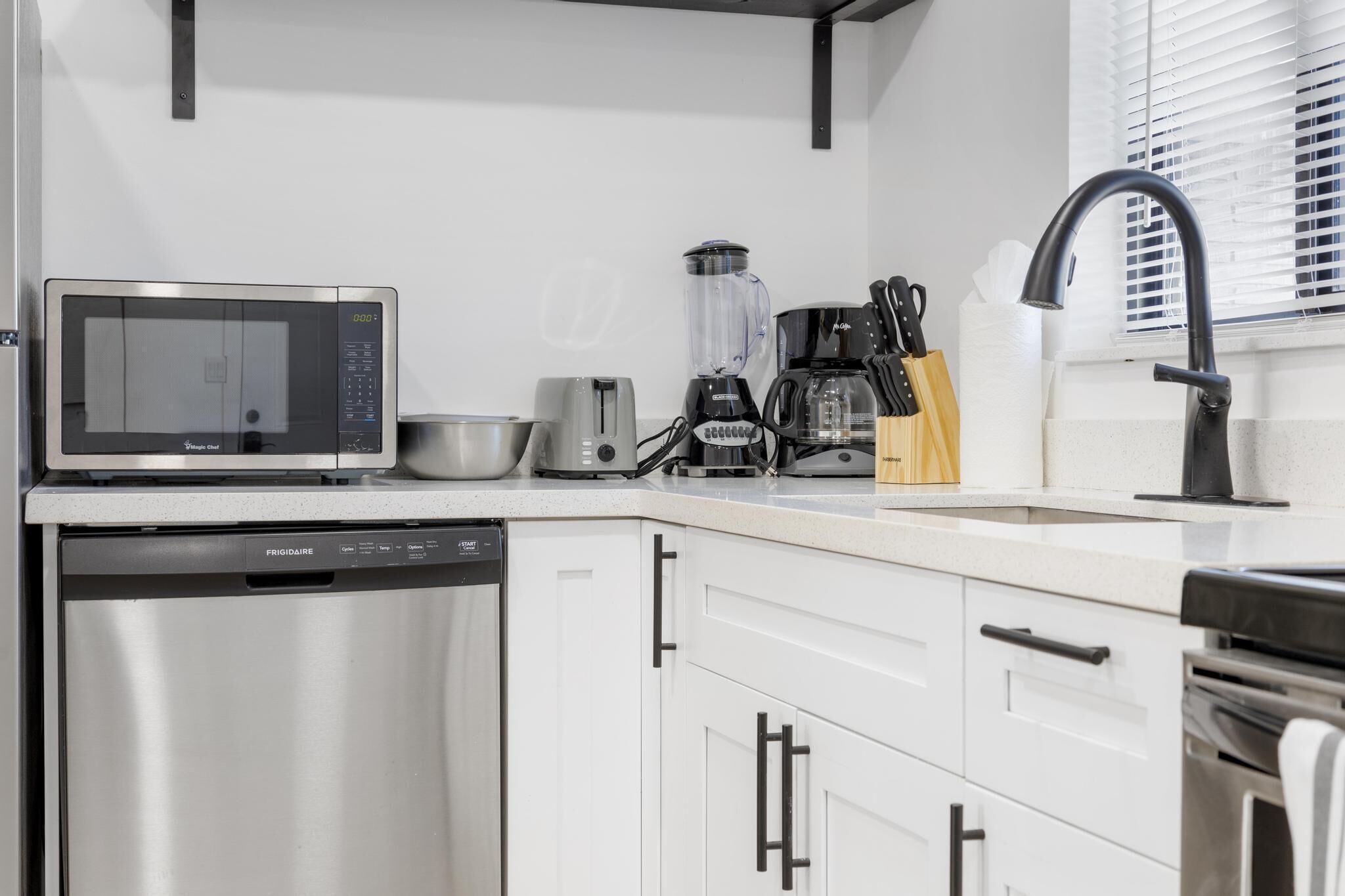 Una cocina moderna equipada con microondas, tostadora, licuadora, cafetera y lavavajillas.